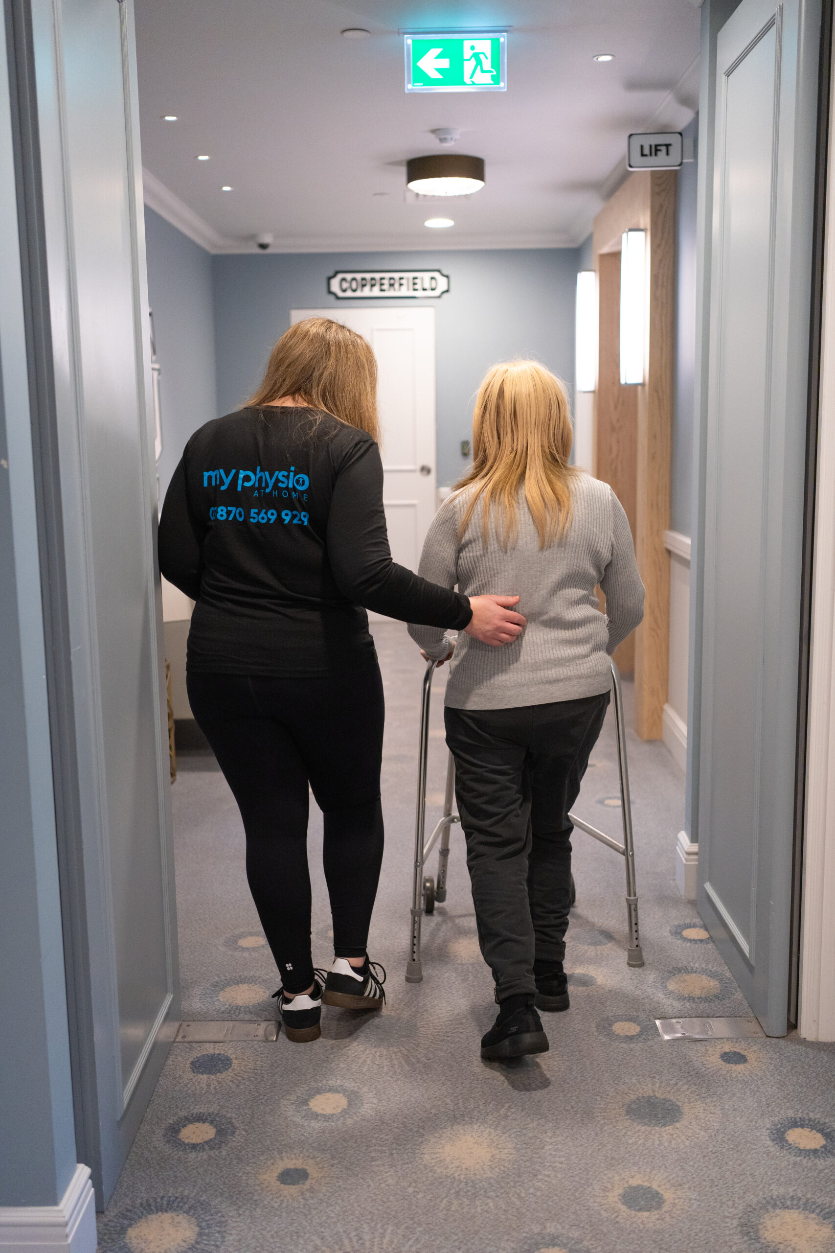 Physio walking with patient using zimmer frame